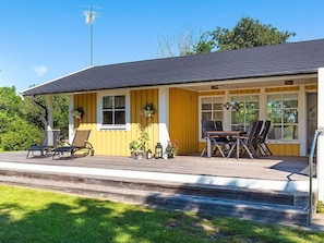 A yellow building with a covered porch, outdoor seating, and a satellite dish.