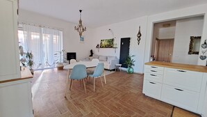 A spacious living area with a dining table, chairs, a sofa, and a kitchen area with cabinets and a countertop.