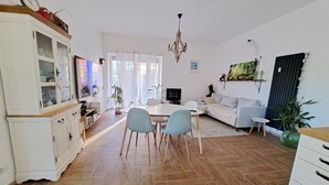 A spacious living room with a dining area, a sofa, a TV, and a chandelier.