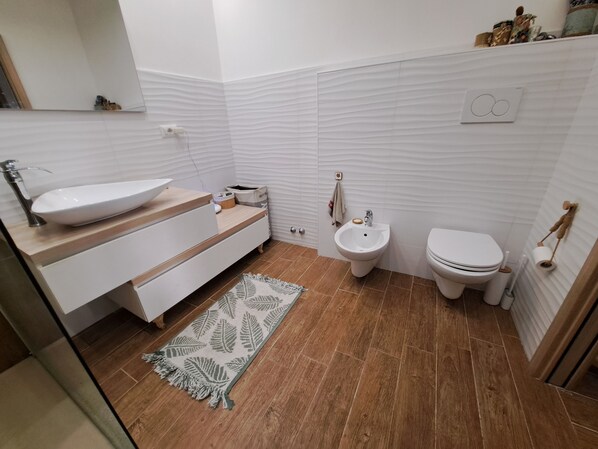 A modern bathroom with a vessel sink, a bidet, and a toilet.