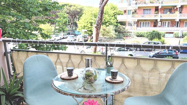 A balcony with two chairs, a small table, and a potted plant.