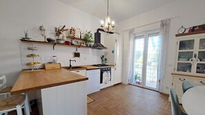 A kitchen with a wooden countertop, white cabinets, a stove, and a dining area with a table and chairs.