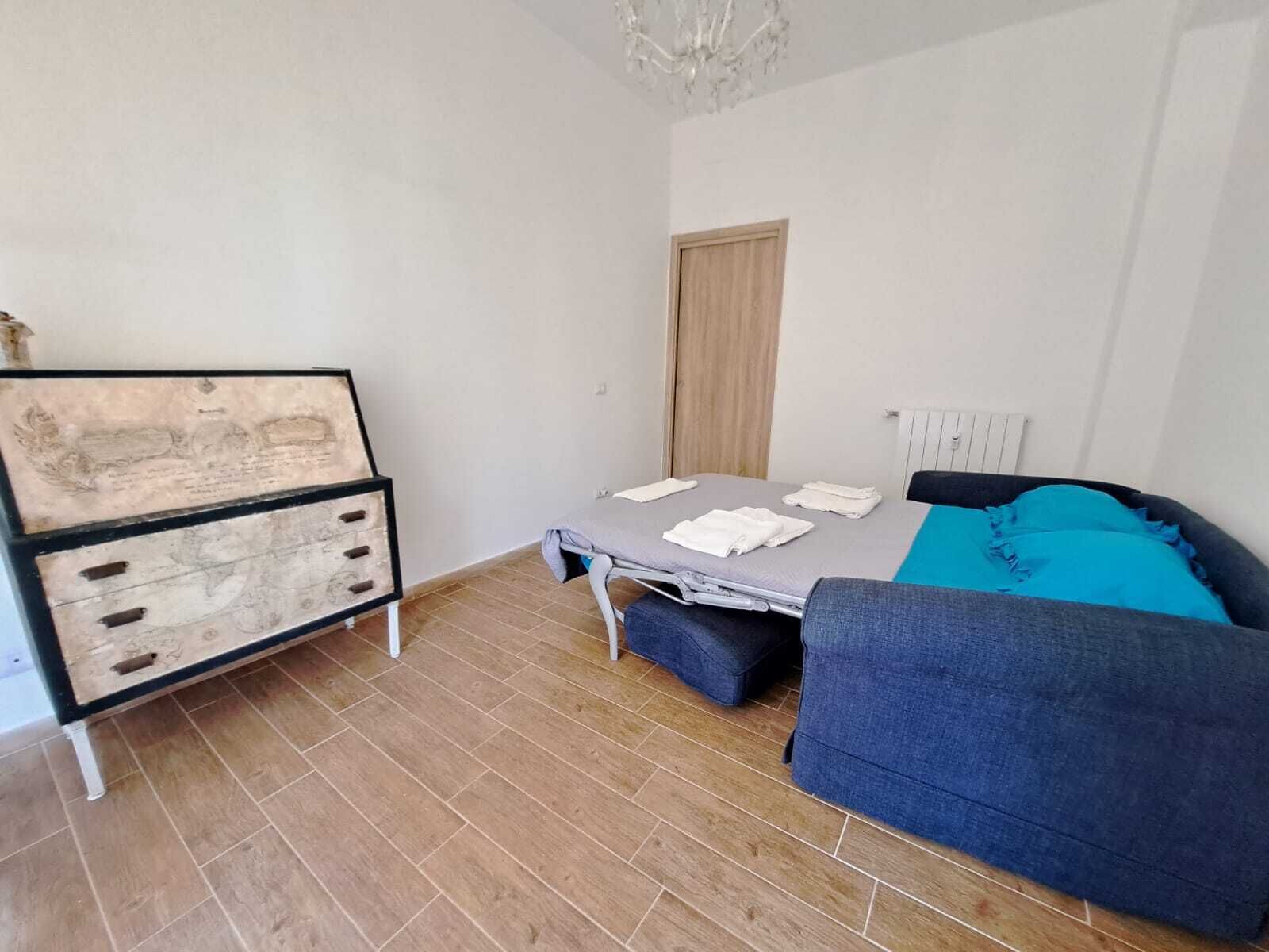 A bedroom with a bed, a dresser, and a blue sofa.