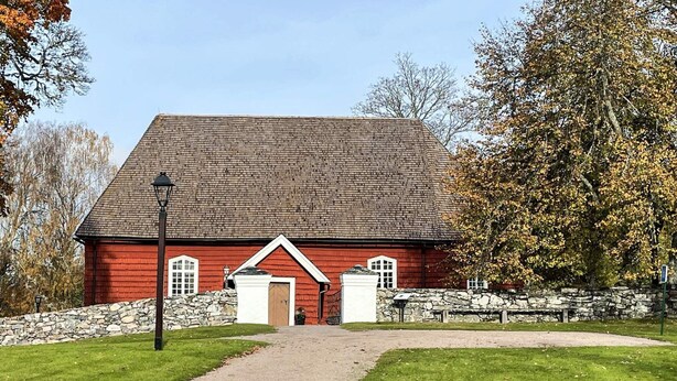 A red barn with a stone wall, a gravel path, and a bench. - 4 Star Holiday Home in Fengersfors (Fengersfors)