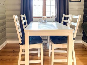 Une table à manger avec six chaises, une fenêtre avec des rideaux et un cœur décoratif accroché au mur.