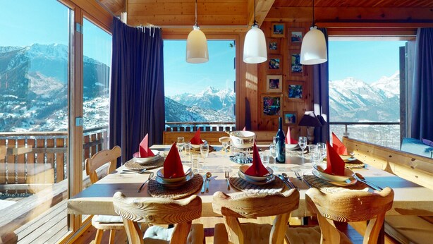 A wooden dining table set with red napkins, glasses, and cutlery, overlooking a snowy mountain landscape. - Chalet in the Heart of Valley With Balcony (Nendaz)