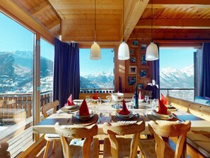 A wooden dining table set with red napkins, glasses, and cutlery, overlooking a snowy mountain landscape. - Chalet in the Heart of Valley With Balcony (Nendaz)