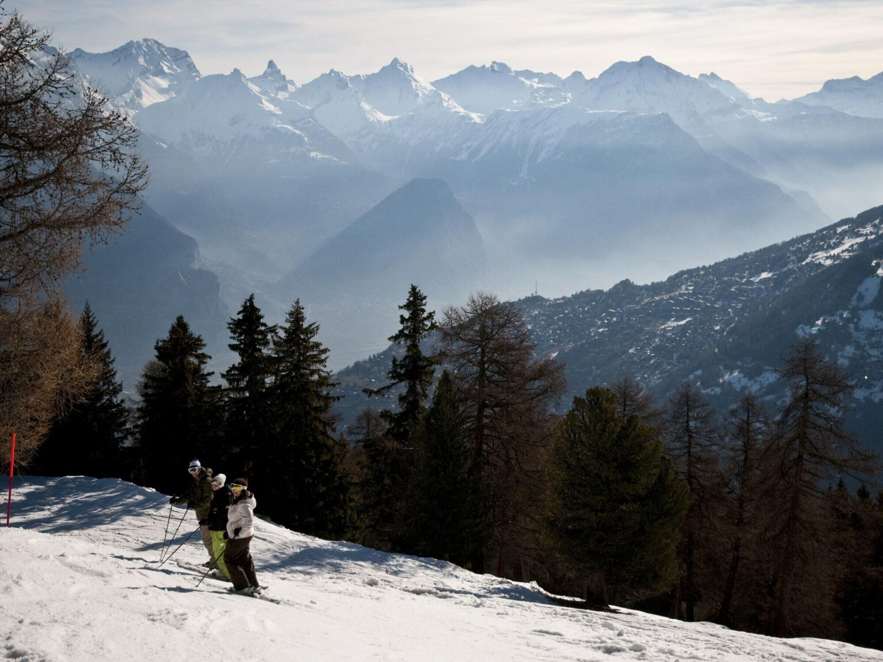 A snowy mountain landscape with skiers.