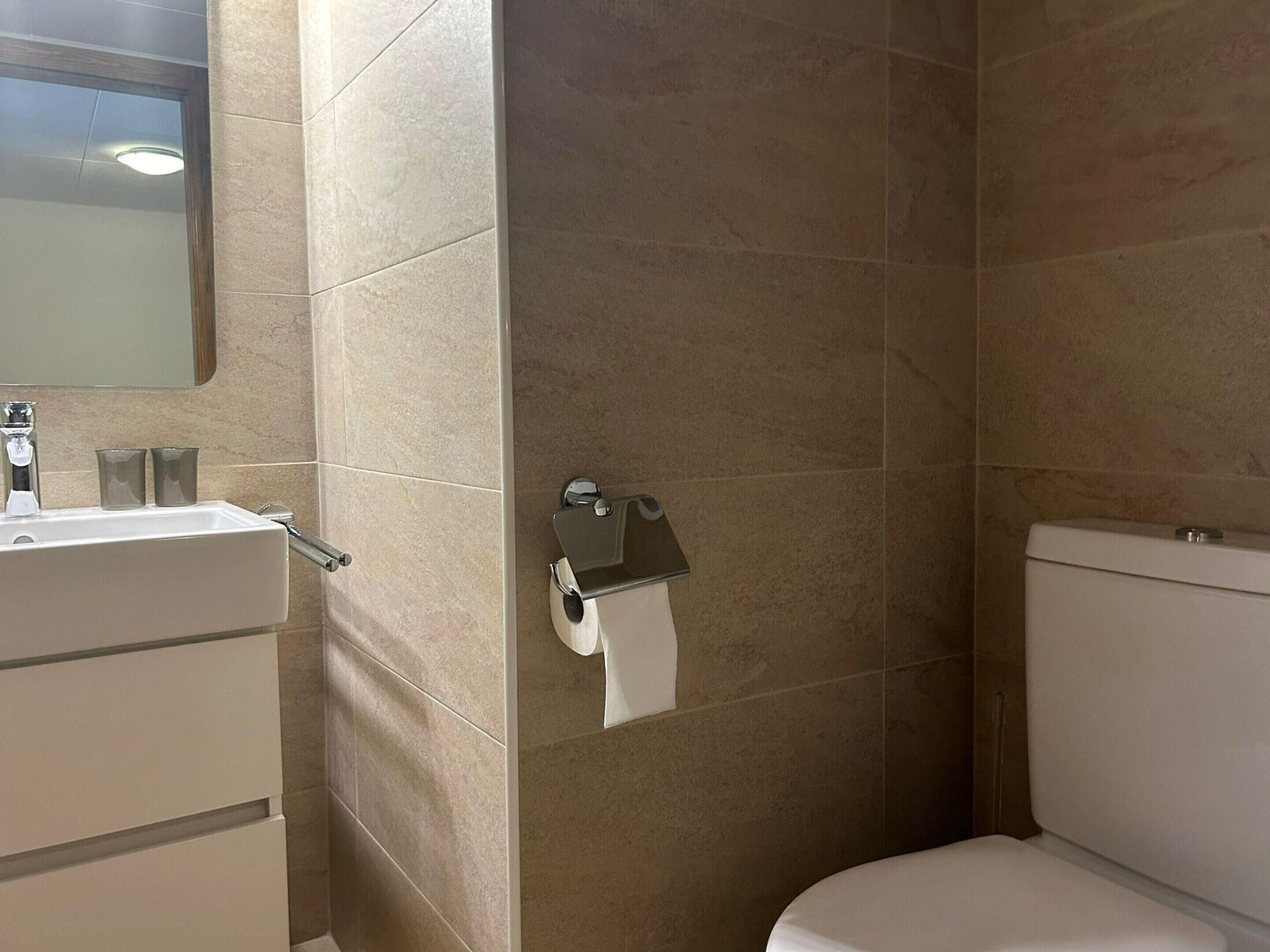 A bathroom with a sink, mirror, toilet, and towel rack.