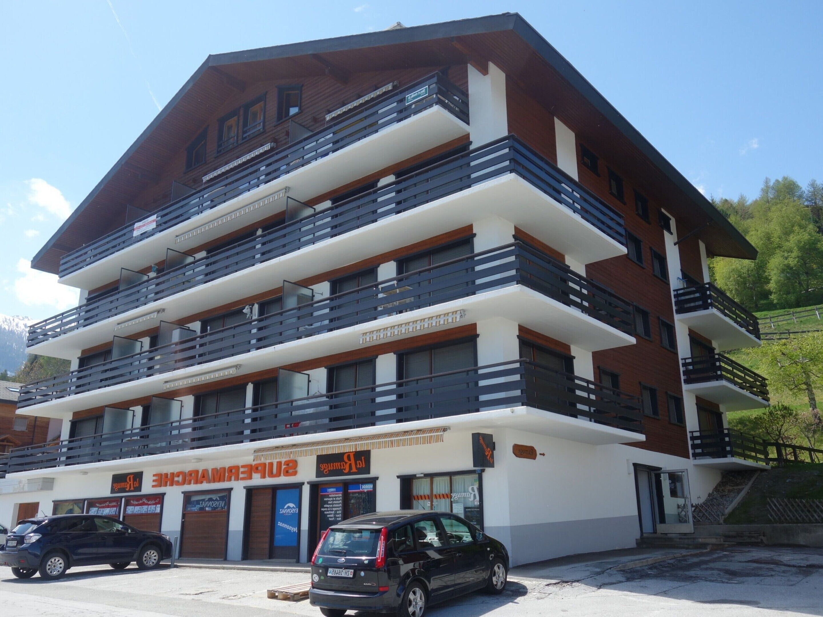 Un hôtel à plusieurs étages doté de balcons, d’un parking et d’une enseigne indiquant la présence d’un restaurant.