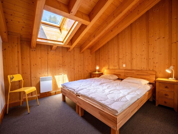 A cozy wooden room with a large bed, a desk, and a chair. - Spacious Chalet With Patio Facing Mountains (Nendaz)
