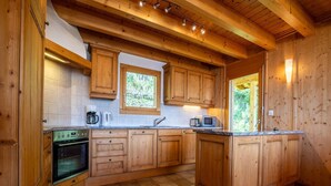 Una cucina in legno con forno a incasso, macchina del caffè e microonde.