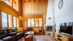 Un soggiorno accogliente con un divano in pelle, un tavolino in legno, un camino in pietra e una TV su un supporto in legno.