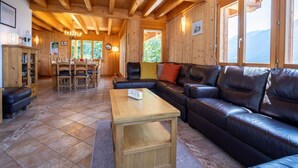 Un interno in legno accogliente con zona pranzo, divano in pelle e ampie finestre che offrono vista sulle montagne.