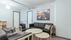 A modern waiting area with a sofa, two chairs, a small table, and a painting of a cliff on the wall. - 3 Person Holiday Home in Thorshavn (Kjellerup)