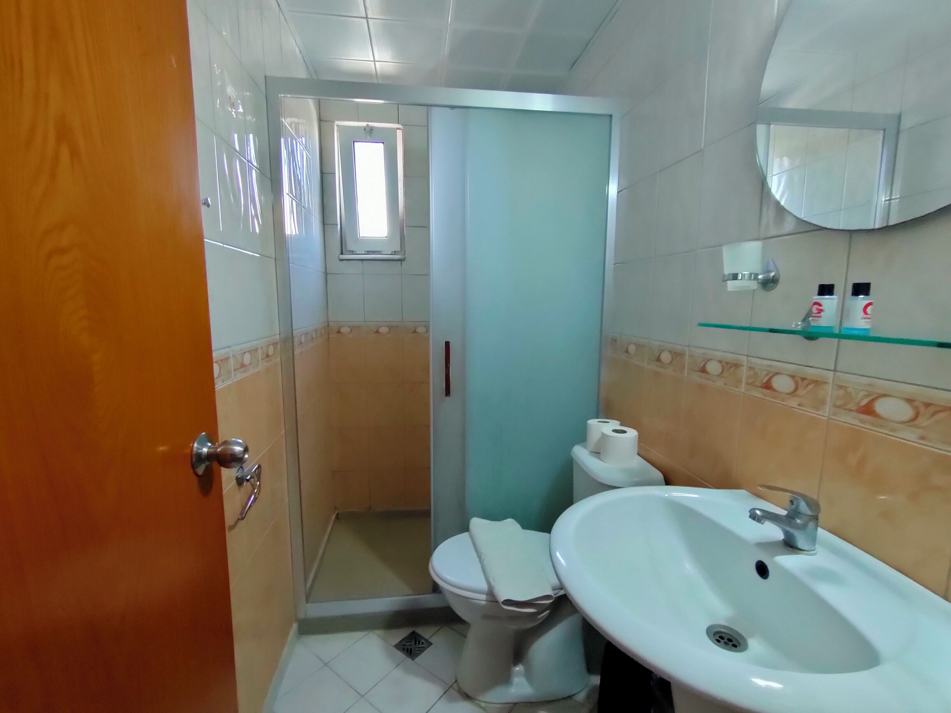 A bathroom with a toilet, sink, and a glass shower enclosure.