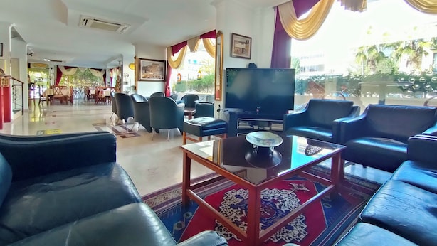 Un vestíbulo de hotel con área de descanso, televisor y vistas al exterior.