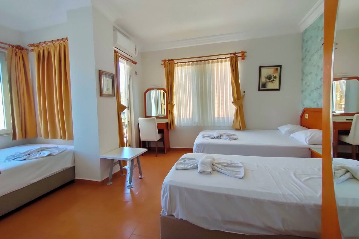 A hotel room with two beds, a desk, and a chair.