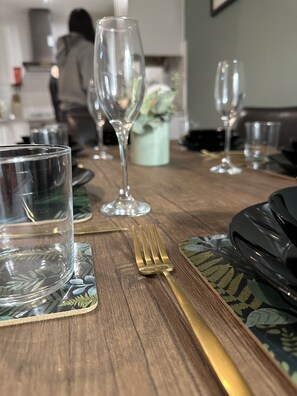 A dining table set with clear glassware, a gold fork, and patterned placemats.