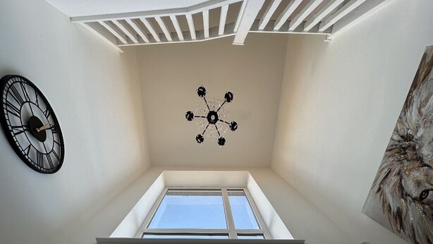 A room with a sloped ceiling, a ceiling fan, a clock, and a painting on the wall. - Bramblemead 5 bed House in Manchester Leigh (Leigh)