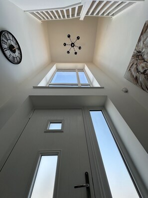 Een kamer met een schuine plafond, een plafondventilator, een klok en een schilderij aan de muur.