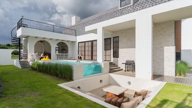 Een modern huis met een zwembad, terras en overdekte veranda.