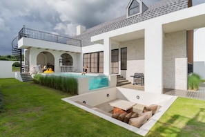 Ein modernes Haus mit Swimmingpool, Sitzgelegenheiten im Freien und einer überdachten Terrasse.