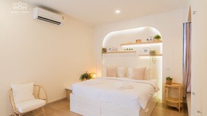 Een slaapkamer met een bed, een stoel, een klein tafeltje en een wandairconditioner.