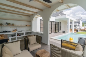 Ein moderner Außenbereich mit Korbmöbeln, einem Pool und Blick auf die umliegende Landschaft.
