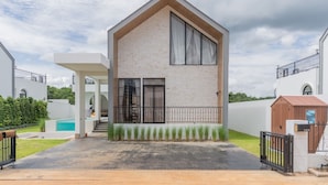 Een modern herenhuis met twee verdiepingen, een groot raam, een overdekt terras en een klein zwembad.