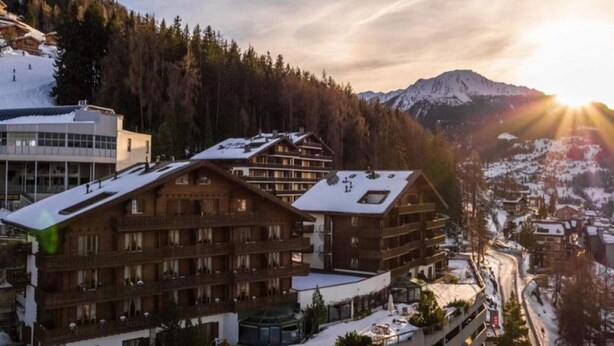 A ski resort with wooden buildings, a parking area, and a mountain backdrop. - Comfortable Apartment With Sauna (Veysonnaz)