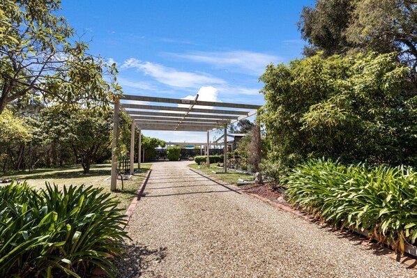 A covered pathway leading to a building with a pergola structure. - Chenu Lakeside Homestead: Your Perfect Holiday Retreat (Eagle Point)