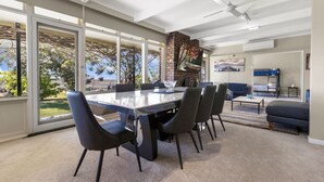 Ruime kamer met een grote eettafel, zachte zithoek, een open haard en grote ramen met uitzicht op de omgeving.