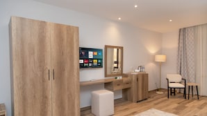 A modern hotel room with a wooden wardrobe, a desk with a flat-screen TV, a mirror, a bedside table, and a chair. - AL Farida Boutique Pyramids (Giza)