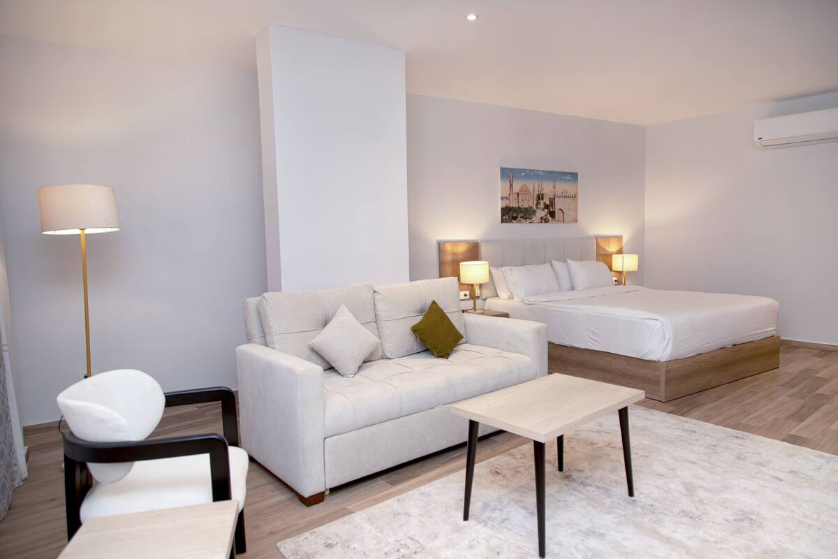Une chambre d’hôtel moderne avec un canapé, un lit, une petite table et une chaise.