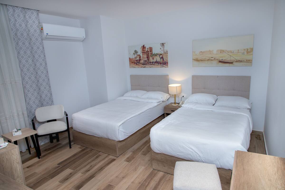 Une chambre d’hôtel avec deux lits simples, un bureau, une chaise et une petite table.