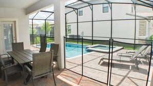 A patio with a glass enclosure, a pool, and outdoor furniture.