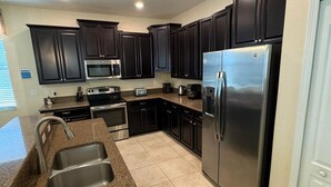 A modern kitchen with dark cabinets, stainless steel appliances, and a granite countertop.