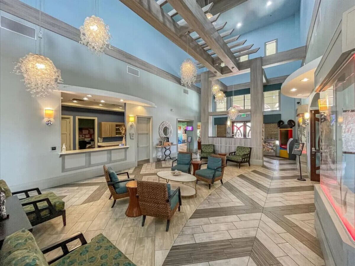 A spacious lobby with a high ceiling, modern furniture, and decorative lighting fixtures.