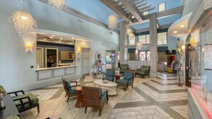 A spacious lobby with a high ceiling, modern furniture, and decorative lighting fixtures.