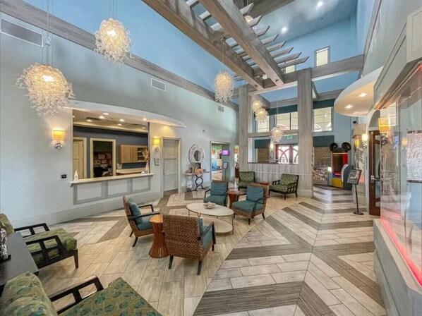 A spacious lobby with a high ceiling, modern furniture, and decorative lighting fixtures.