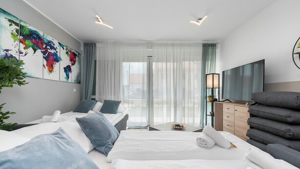 Quarto de hotel moderno com duas camas, uma janela grande com cortinas, uma TV de tela plana, uma cômoda e uma pintura de um mapa-múndi na parede.