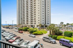 Un parking à plusieurs étages avec plusieurs voitures, un chemin piétonnier et un grand immeuble doté de balcons.