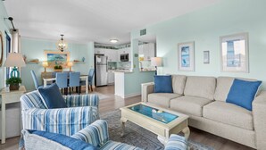 Ein Wohnzimmer mit einer Couch, Sesseln, einem Couchtisch und einem Essbereich mit Stühlen und einem Tisch.