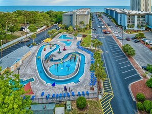 A resort with a pool area, including a water slide and lounge chairs, surrounded by parking and a view of the ocean. - A311 at the Myrtle Beach Resort (Myrtle Beach)