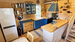 A compact kitchen with a refrigerator, blue cabinets, wooden countertops, and a small dining area. - 7 Person Holiday Home in Lyngdal (Lyngdal)