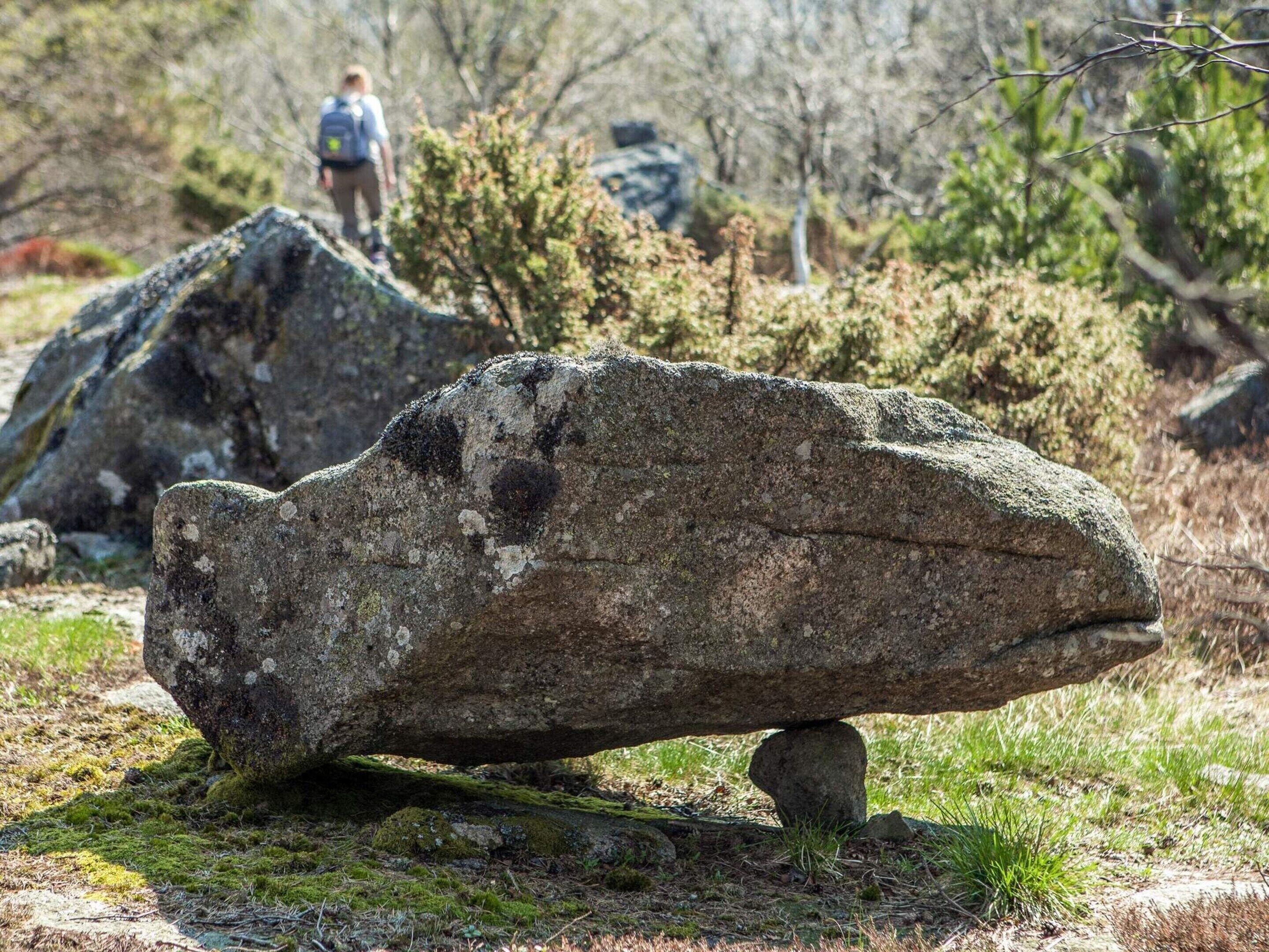 A large rock formation with moss and a smaller rock balanced on top.