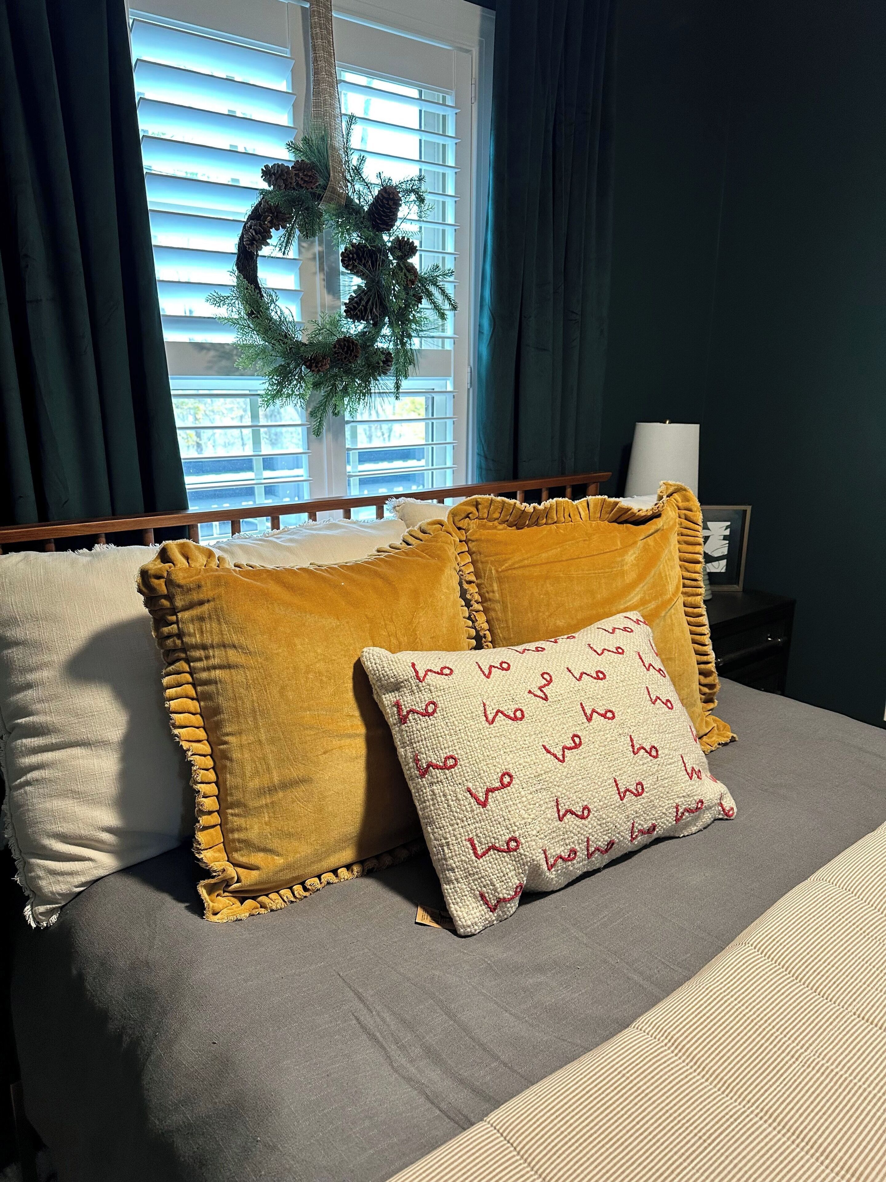 A bed with a grey mattress, two mustard-colored pillows, and a white pillow with red text.