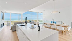 A modern kitchen with a large island, a dining area with a view of the beach, and a spacious living area with a large window overlooking the ocean. - Casa Bianca 50 Esplanade Middleton (Middleton)