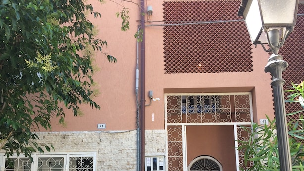 Una escalera conduce a un edificio de fachada de piedra, puertas de metal y un letrero con el número 42.